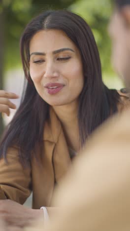 Vertical-Video-Close-Up-Of-Muslim-Couple-On-Date-Meeting-And-Talking-At-Table-On-City-Street-Together